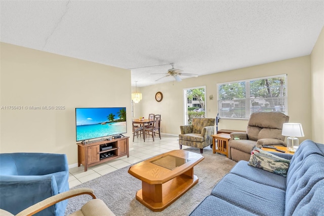 living room with ceiling fan, light tile patterned flooring, baseboards, and a textured ceiling