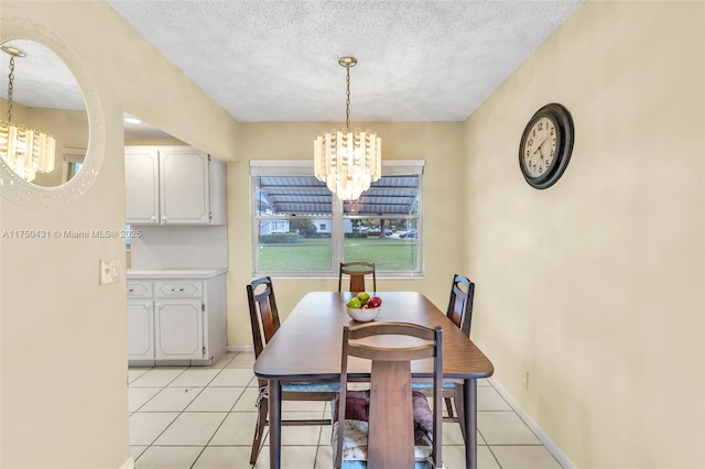 dining room featuring a textured ceiling, an inviting chandelier, baseboards, and light tile patterned floors