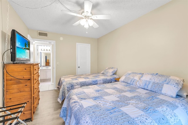 bedroom with connected bathroom, light wood-type flooring, a textured ceiling, a ceiling fan, and visible vents