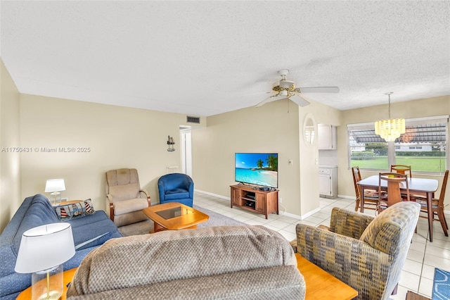living area featuring ceiling fan with notable chandelier, light tile patterned floors, a textured ceiling, visible vents, and baseboards