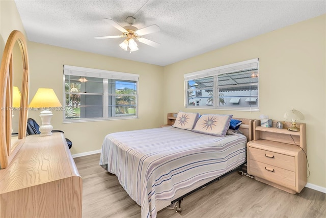 bedroom with a textured ceiling, light wood finished floors, and baseboards