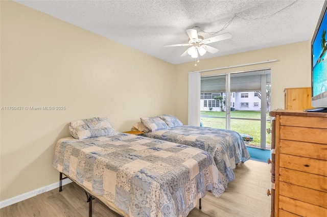 bedroom with a textured ceiling, wood finished floors, ceiling fan, and baseboards