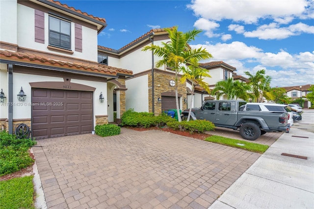 view of front facade with stone siding, a tiled roof, decorative driveway, and stucco siding