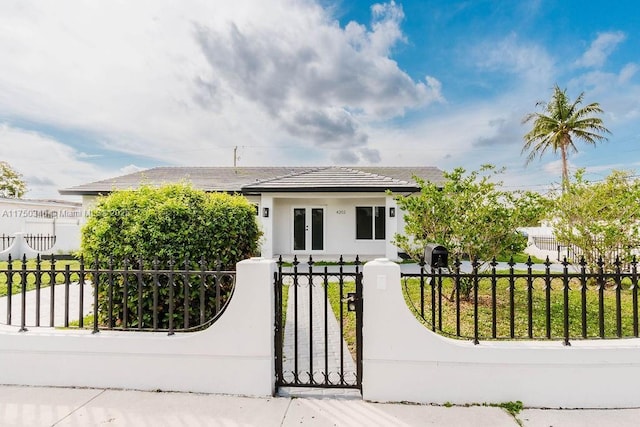 view of front of property featuring a fenced front yard, a tile roof, and stucco siding