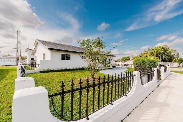 view of front facade with a fenced front yard, a front yard, and stucco siding