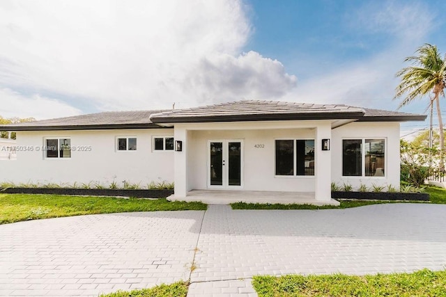 back of property with stucco siding, a patio, and french doors