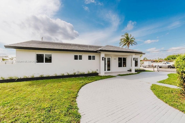 view of front of home with driveway, fence, a front lawn, and stucco siding