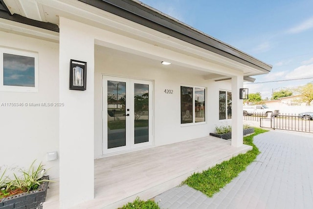 view of exterior entry featuring fence and stucco siding