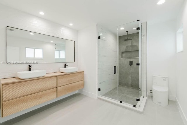 bathroom with toilet, a sink, a marble finish shower, and double vanity