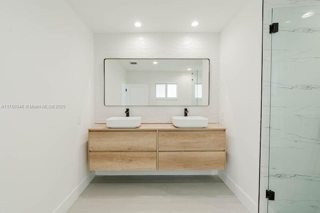 full bathroom with double vanity, a sink, a marble finish shower, and recessed lighting
