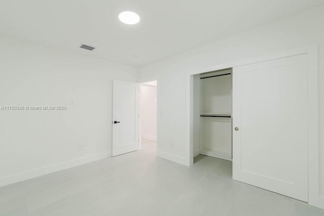 unfurnished bedroom with baseboards, visible vents, and a closet