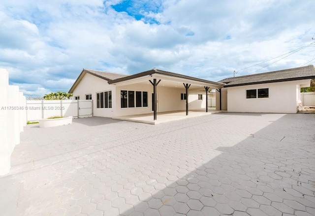 rear view of property with a patio area, fence, and stucco siding