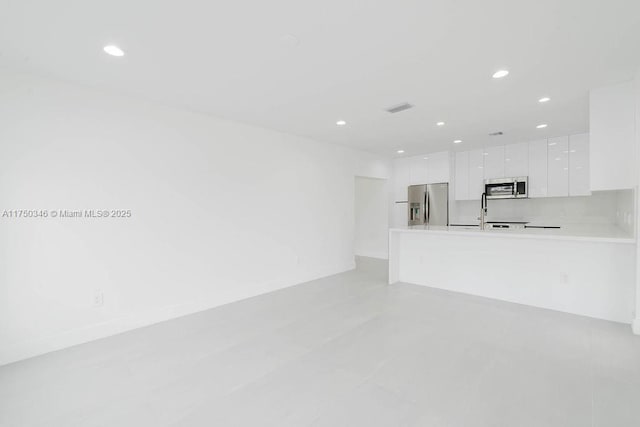 unfurnished living room featuring recessed lighting, visible vents, and a sink
