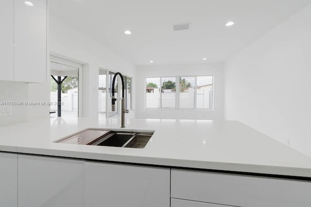 kitchen featuring recessed lighting, light countertops, white cabinets, a sink, and modern cabinets