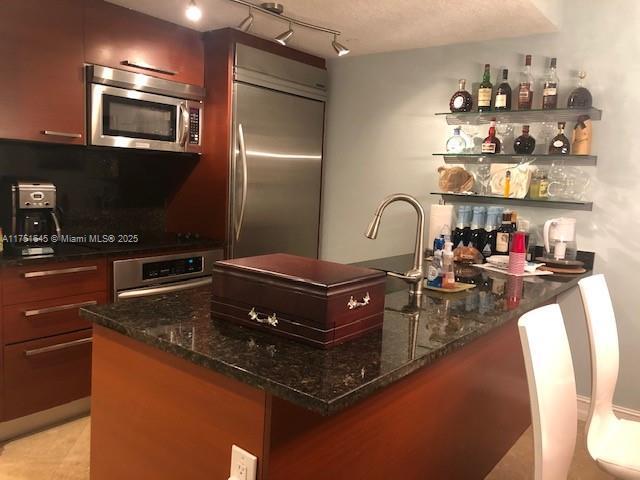 kitchen featuring light tile patterned floors, open shelves, appliances with stainless steel finishes, and dark stone countertops