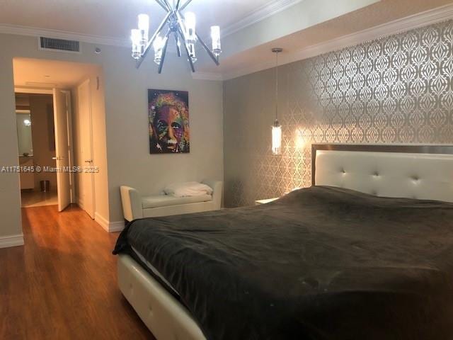 bedroom with baseboards, wood finished floors, visible vents, and crown molding