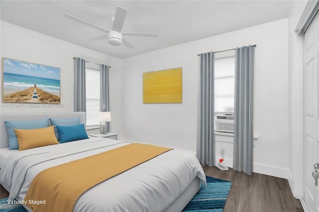 bedroom with baseboards, multiple windows, cooling unit, and wood finished floors