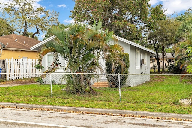 view of property exterior with a fenced front yard, a lawn, and stucco siding