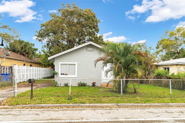 view of front of home with a fenced front yard, a front lawn, and stucco siding