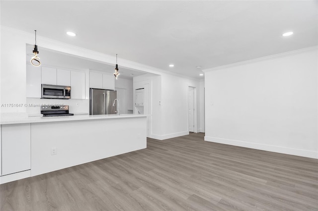 kitchen with stainless steel appliances, wood finished floors, white cabinetry, hanging light fixtures, and light countertops