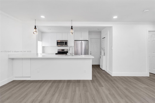 kitchen with white cabinets, appliances with stainless steel finishes, light countertops, and decorative light fixtures
