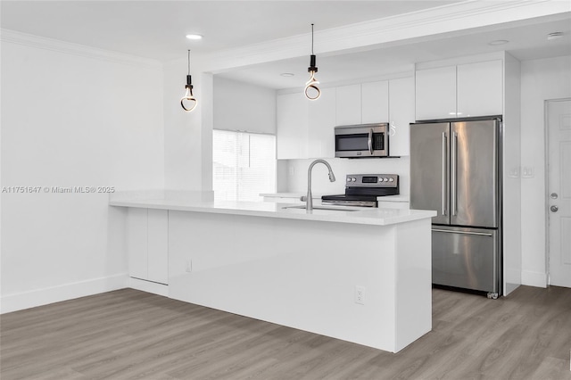 kitchen with decorative light fixtures, stainless steel appliances, light countertops, white cabinetry, and a peninsula