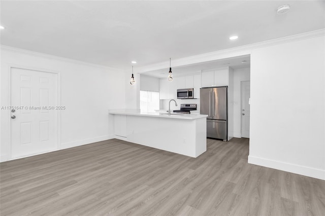 kitchen featuring stainless steel appliances, a peninsula, white cabinets, light countertops, and ornamental molding
