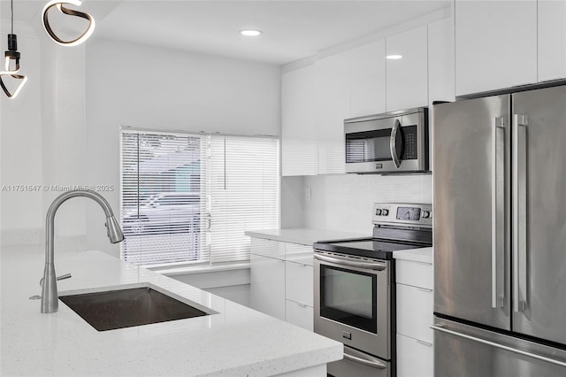kitchen featuring modern cabinets, appliances with stainless steel finishes, hanging light fixtures, light stone countertops, and white cabinetry