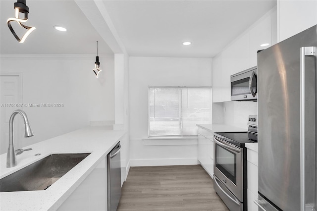 kitchen featuring stainless steel appliances, a sink, white cabinets, light stone countertops, and pendant lighting