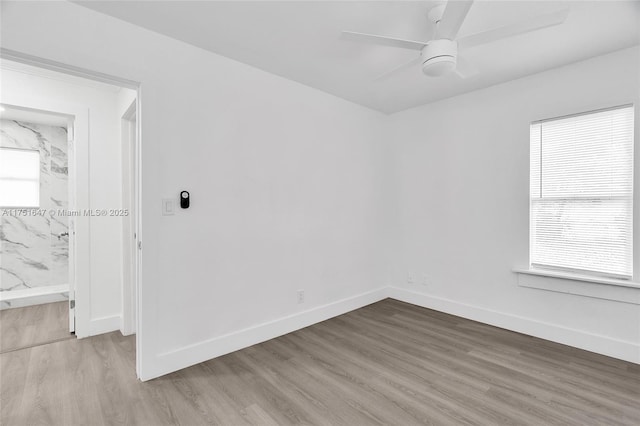 spare room featuring light wood-type flooring, baseboards, and a ceiling fan