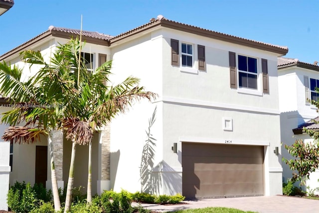 mediterranean / spanish-style home featuring stucco siding, a garage, driveway, and a tiled roof