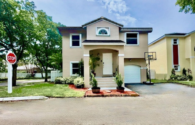 view of front of house with a garage, fence, driveway, and stucco siding