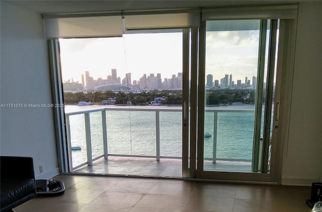 doorway to outside with tile patterned flooring, a view of city, baseboards, and a water view