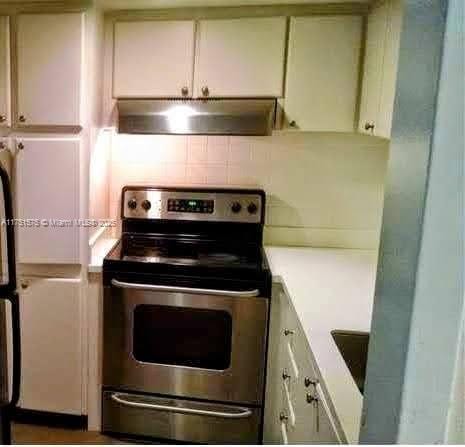 kitchen with light countertops, stainless steel electric range oven, under cabinet range hood, and white cabinetry