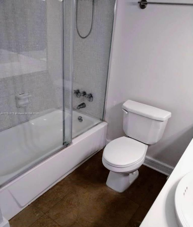 bathroom featuring baseboards, bath / shower combo with glass door, toilet, and tile patterned floors