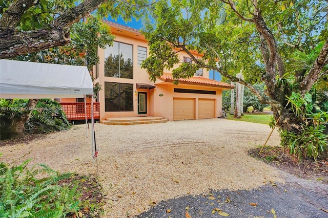 view of front of home with a garage, driveway, a tiled roof, and stucco siding