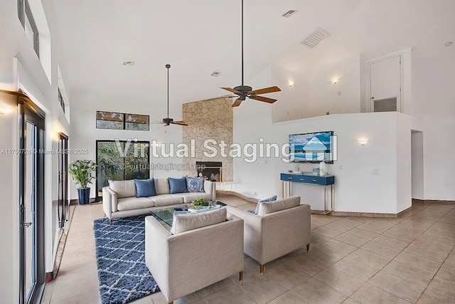 living area featuring a stone fireplace, visible vents, and a towering ceiling