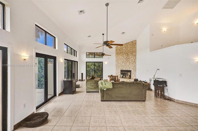 living room featuring ceiling fan, visible vents, a fireplace, and light tile patterned floors