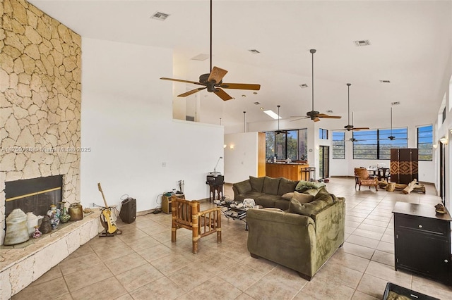 living room with a towering ceiling, a fireplace, visible vents, and light tile patterned flooring