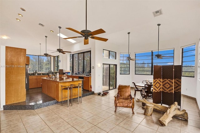 kitchen featuring brown cabinetry, visible vents, a center island with sink, and light tile patterned flooring