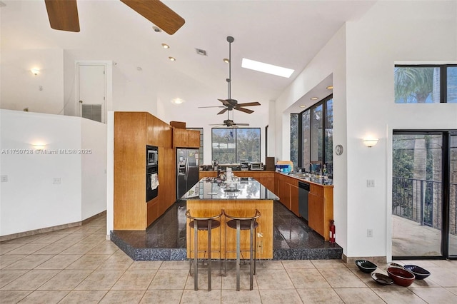 kitchen featuring stainless steel appliances, a healthy amount of sunlight, high vaulted ceiling, and brown cabinets