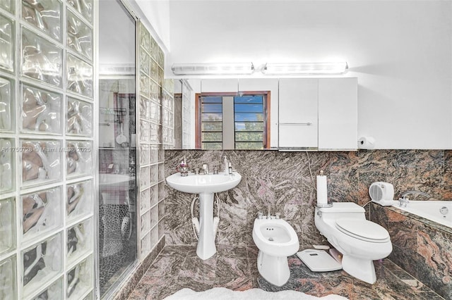 bathroom featuring a garden tub, toilet, a stall shower, a bidet, and a sink