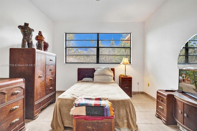 bedroom featuring multiple windows, light tile patterned flooring, and baseboards