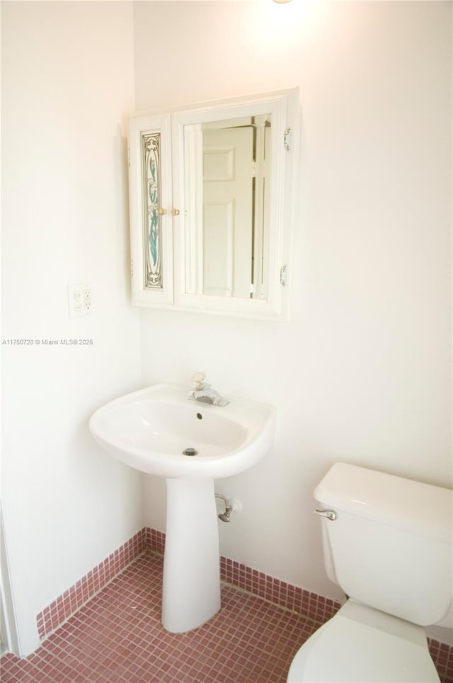 half bath with tile patterned flooring and toilet