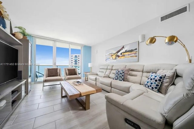 living area with a water view, visible vents, and floor to ceiling windows