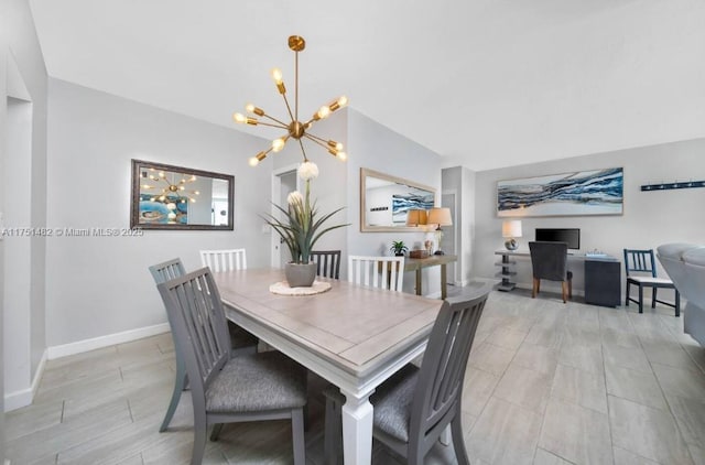 dining area with baseboards, lofted ceiling, and a notable chandelier