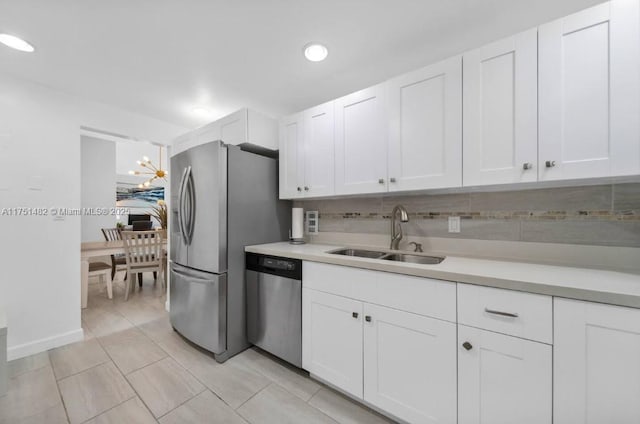 kitchen featuring appliances with stainless steel finishes, light countertops, a sink, and white cabinetry