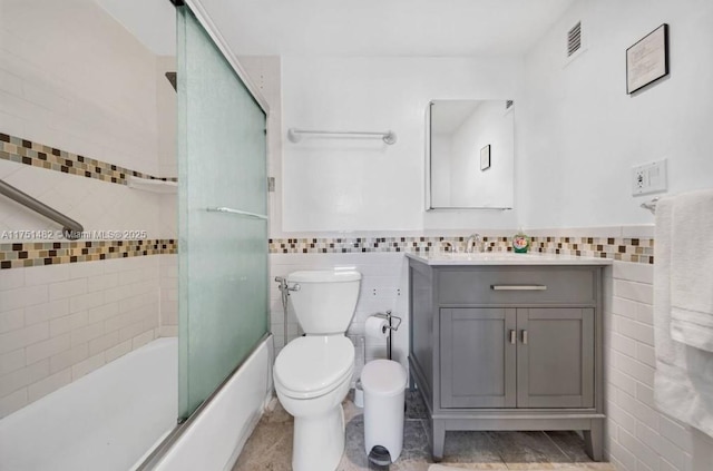 full bath featuring enclosed tub / shower combo, visible vents, tile walls, and vanity