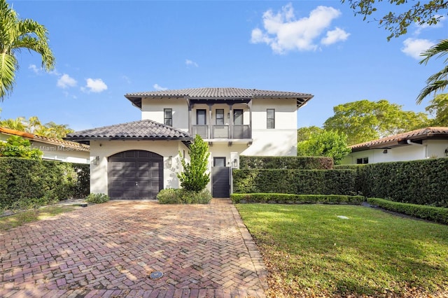 mediterranean / spanish home with decorative driveway, an attached garage, fence, and a balcony