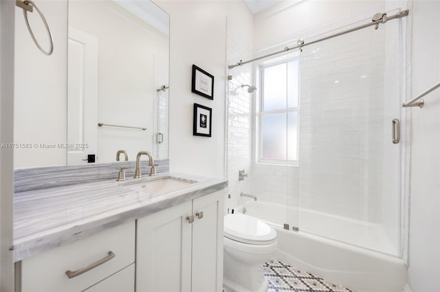 bathroom featuring toilet, shower / bath combination with glass door, and vanity